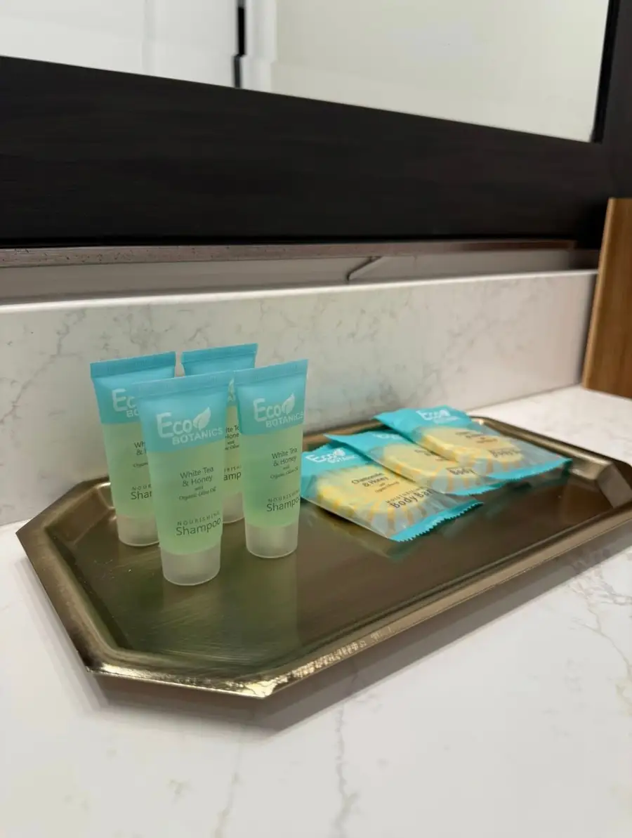 Guest shampoo and soap bars set out on a brass tray by the bathroom mirror
