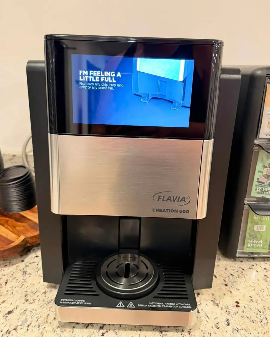 The same coffee machine clean and dry, with the coffee and tea packs restocked beside it