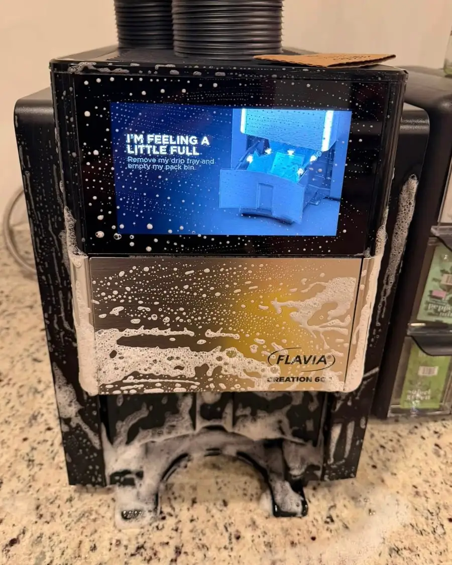Coffee machine covered in cleaning foam in the middle of a scrub