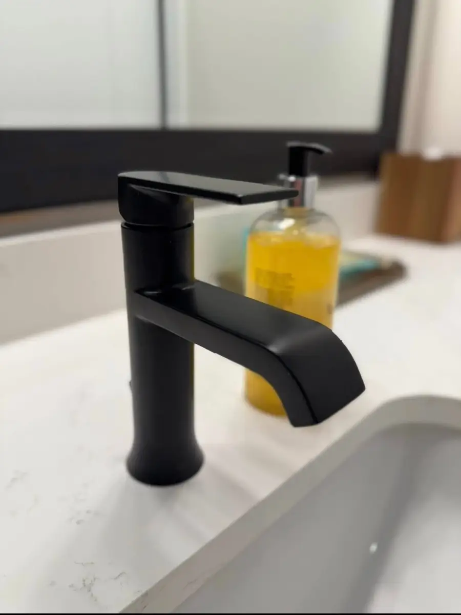 Matte black bathroom faucet and a soap pump on a clean white counter