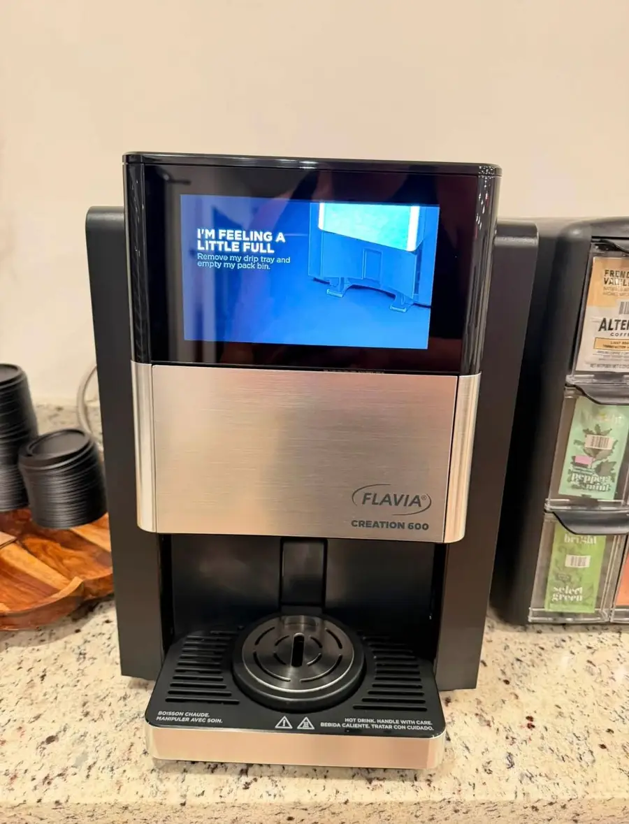 The same coffee machine clean and dry, with the coffee and tea packs restocked beside it