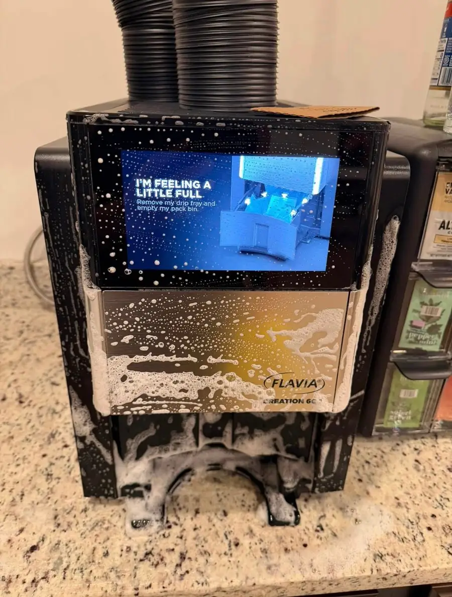 Coffee machine covered in cleaning foam in the middle of a scrub