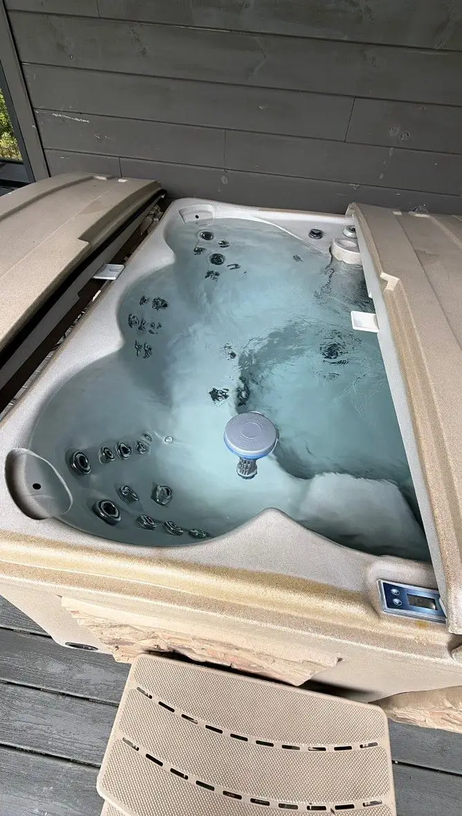 Cabin hot tub on a deck, cleaned and refilled with clear water, cover folded back