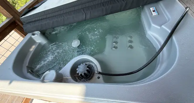 Hot tub being refilled with a hose after draining, filter in place