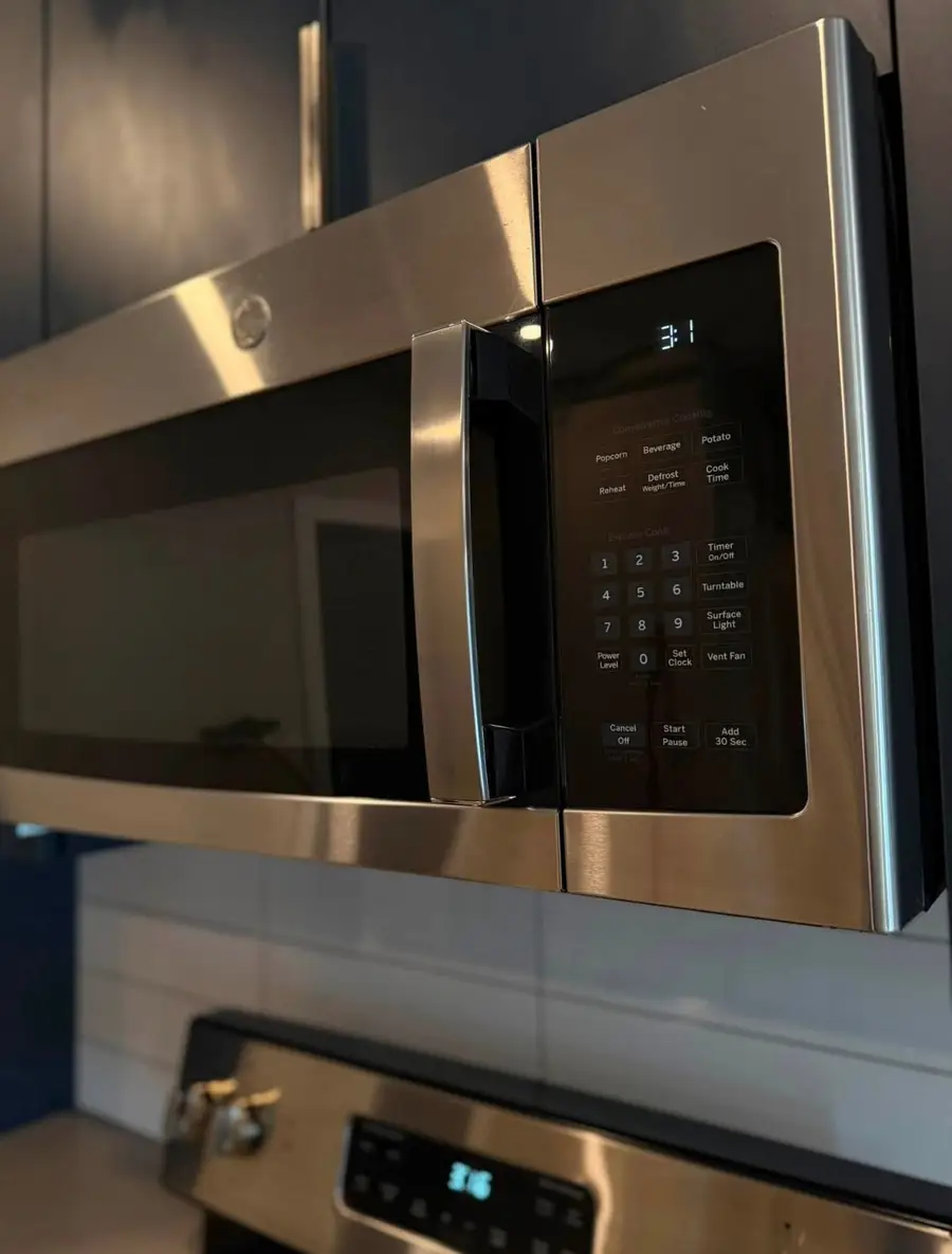 Stainless steel over-the-range microwave wiped clean, stovetop below