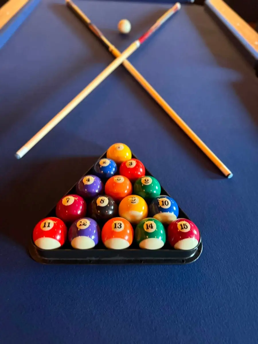 Pool balls racked and two cues crossed on a blue pool table