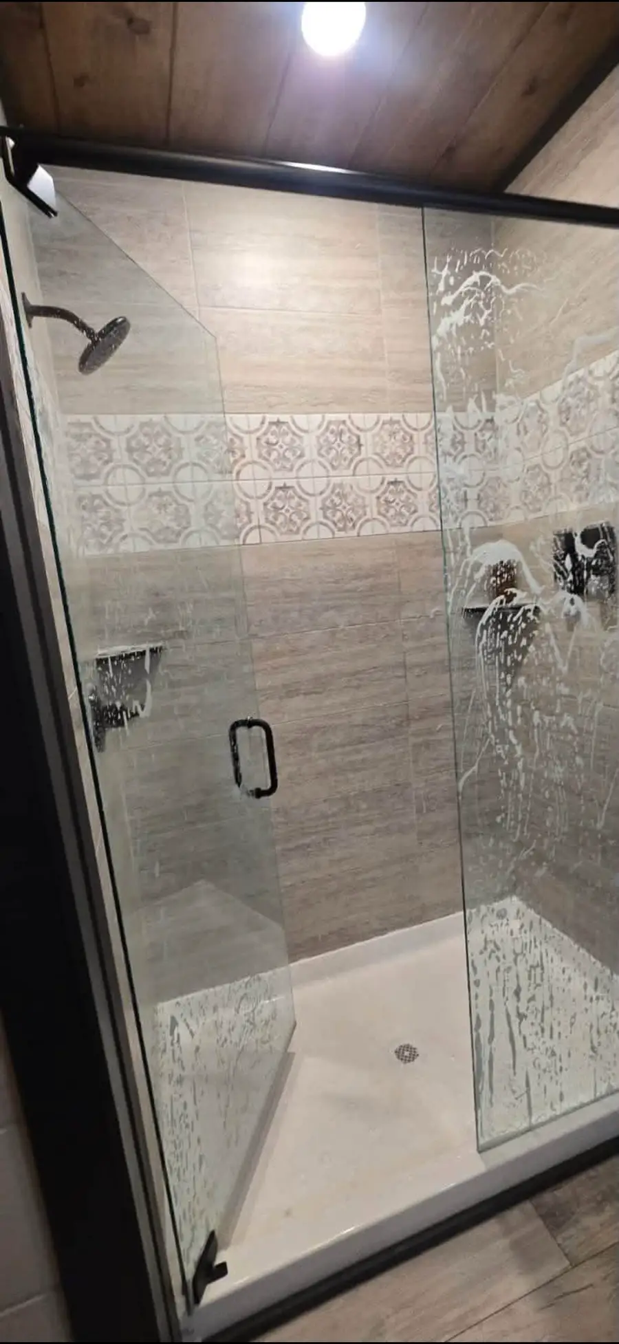 Glass shower door covered in cleaning foam during a bathroom deep clean