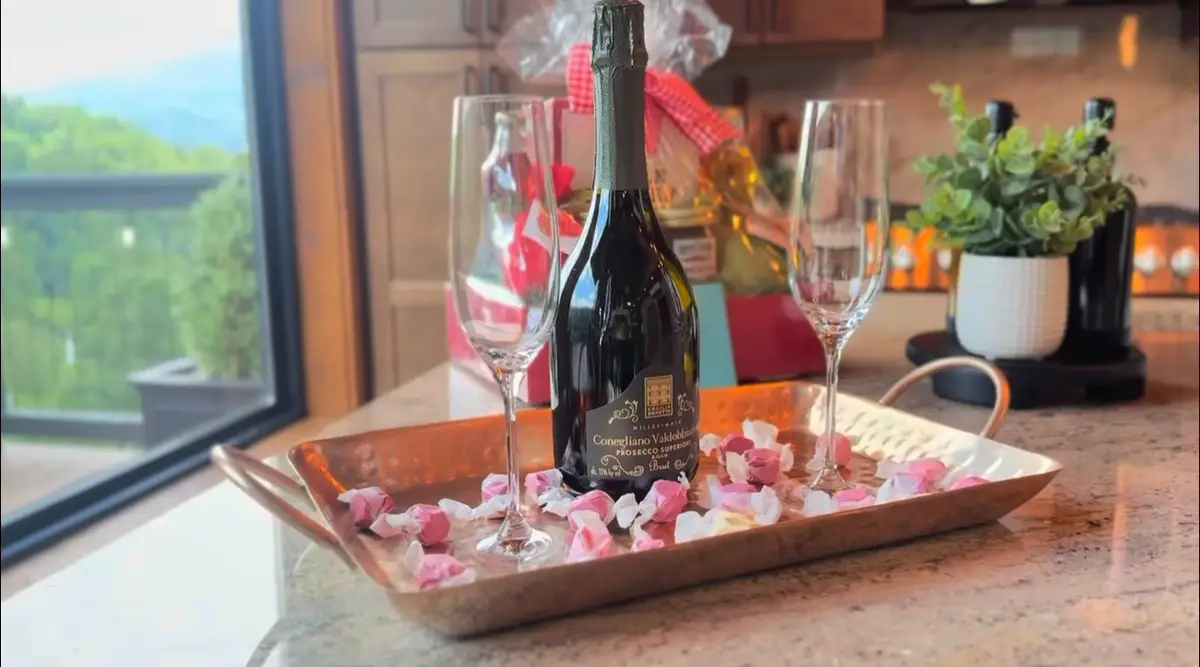 Welcome tray with sparkling wine, two glasses and candy by a window with a mountain view